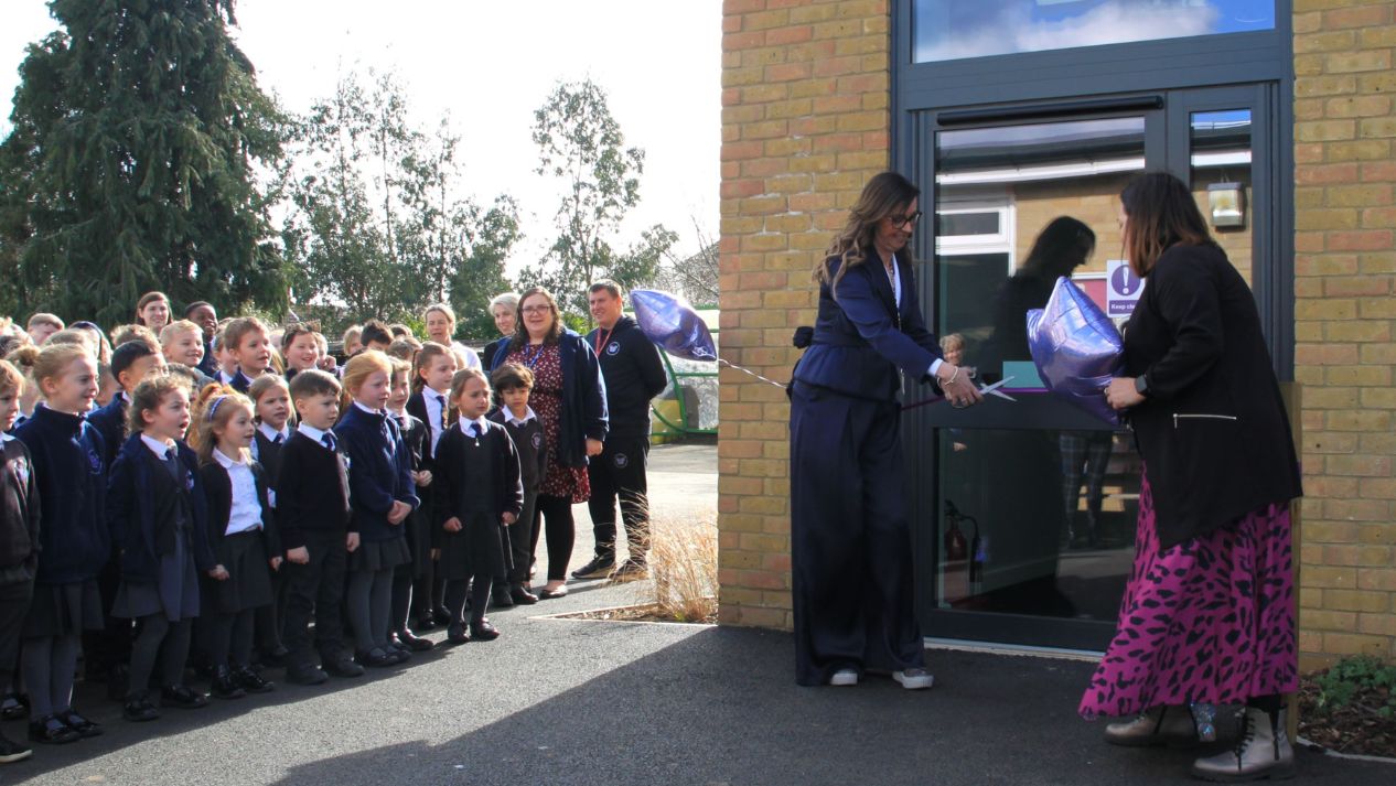 Children and pupils celebrating completion with ribbon cutting